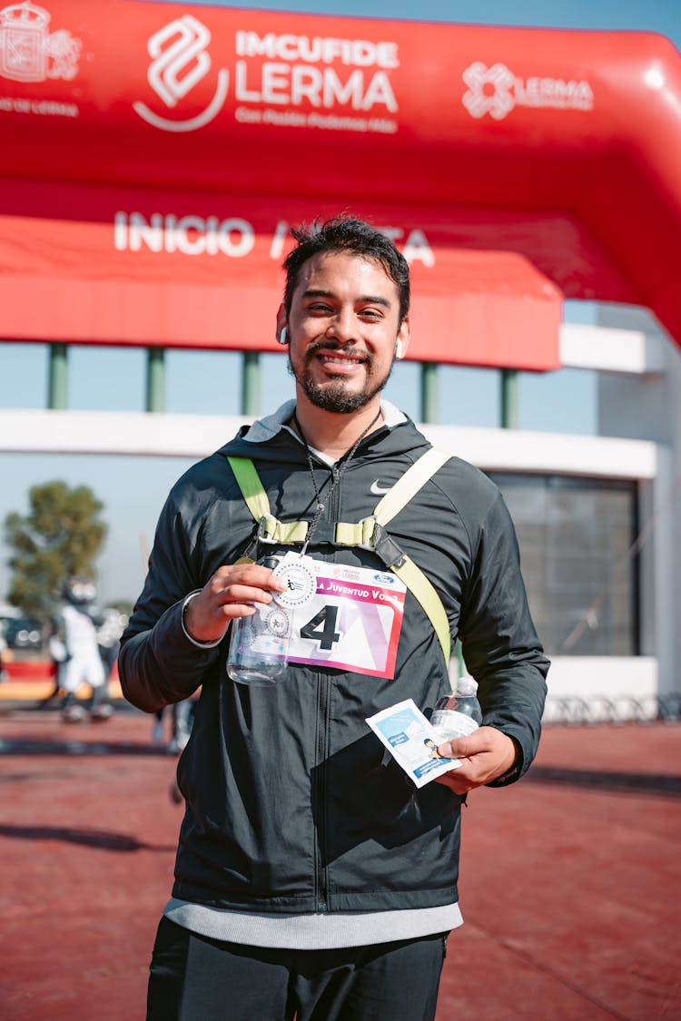 Man With Medal And Bottle Of Water Standing On Meta After Run