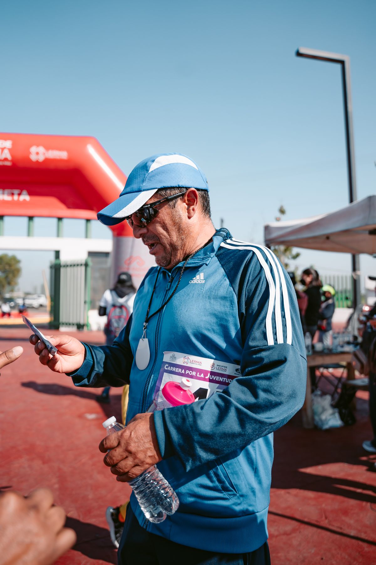 Athlete in sportswear holding a smartphone outdoors after a race