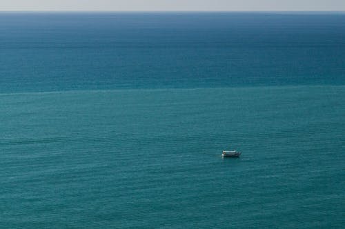 A boat is floating in the ocean near a cliff