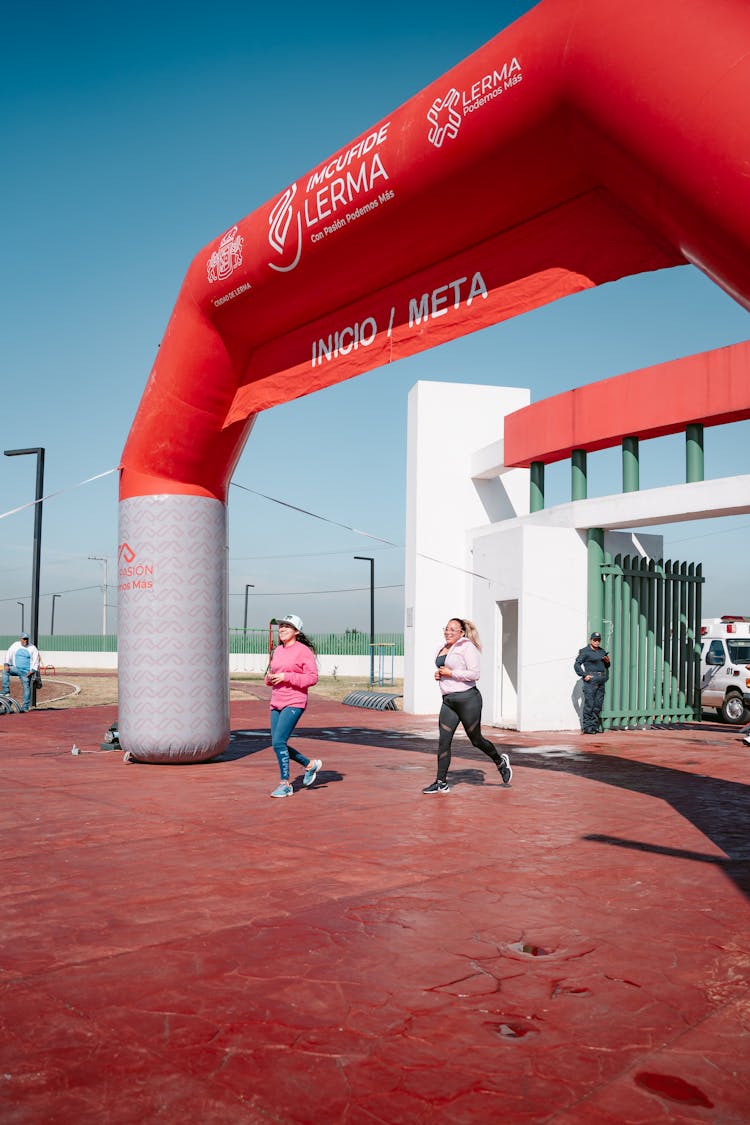 Women Running Through Start And Finish Gate