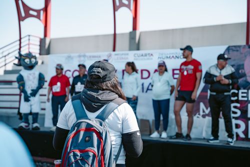 Free Participants gather on stage for an outdoor sporting event, with a woman in the foreground. Stock Photo