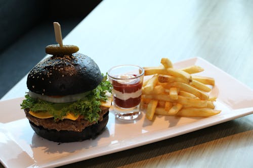 Imágenes gratuitas de papas fritas con salsa en vaso de chupito y hamburguesas con pan negro en una bandeja