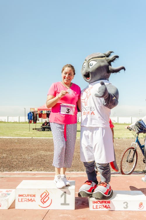 Woman Standing with Mascot on Podium