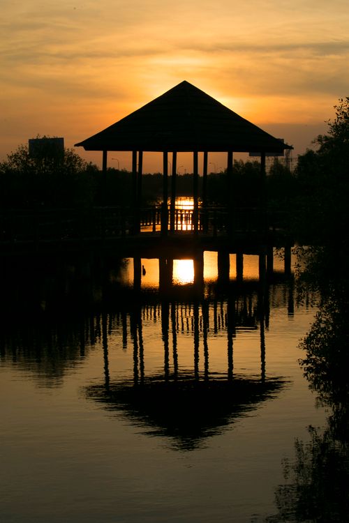 Free Peaceful sunset silhouette and reflection of a gazebo over calm water. Stock Photo