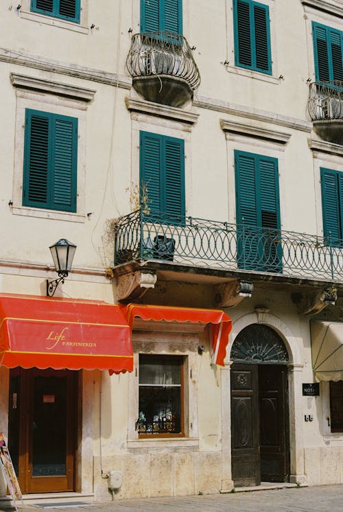 Old Town Building Facade with Window Shutters and Red Sunshades