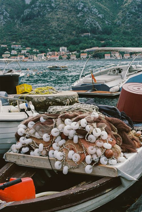 Free Fishing boats with nets in a serene harbor with mountain backdrop. Stock Photo