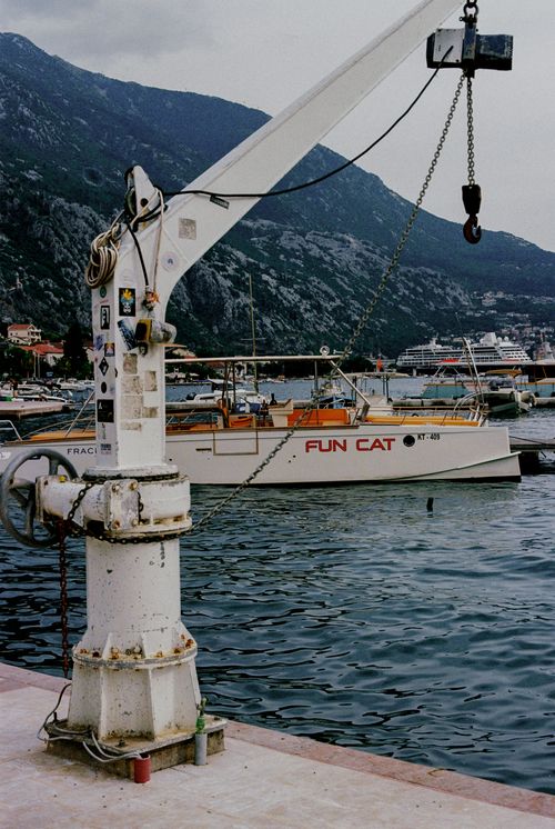 Free A scenic harbor view showcasing boats, a crane, and a coastal mountain backdrop. Stock Photo