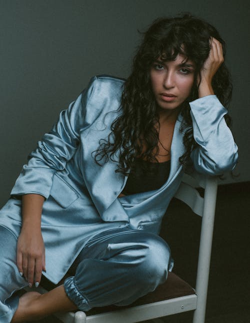 Studio Shoot of a Woman Wearing a Blue Silky Suit, Sitting on a Chair