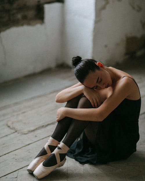 A Ballerina Sitting on the Floor in an Abandoned Building 