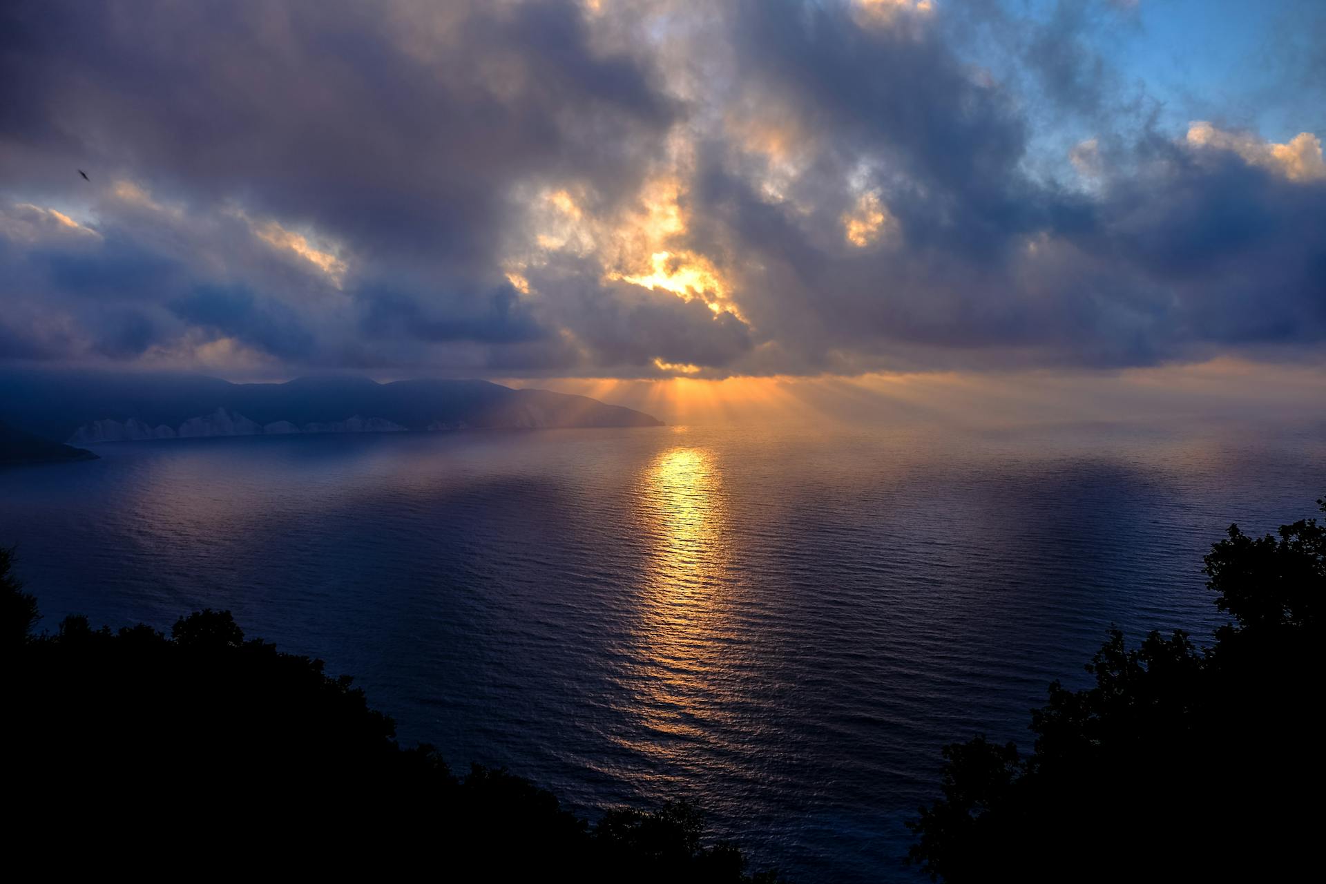 Dramatic sunset over the Ionian Sea in Kefallonia, Greece, with vibrant colors and cloud formations.