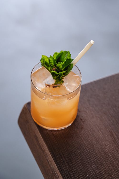 Juice with Ice Cubes and Mint Leaves in a Corner of a Wooden Table