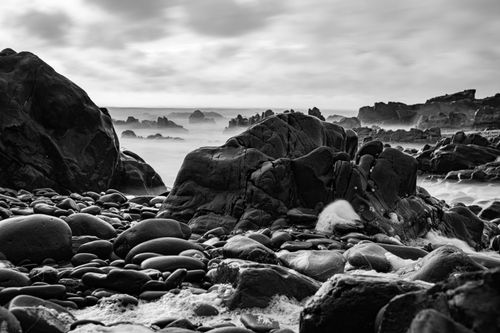 Free Black and white photo of rugged rock formations along the coast of Bude, England, showcasing nature's raw beauty. Stock Photo