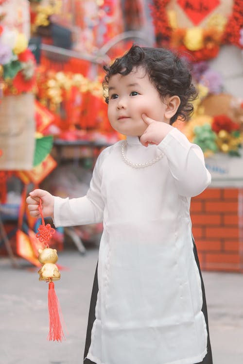 Photo of a Baby Girl Holding a Festive Pendant