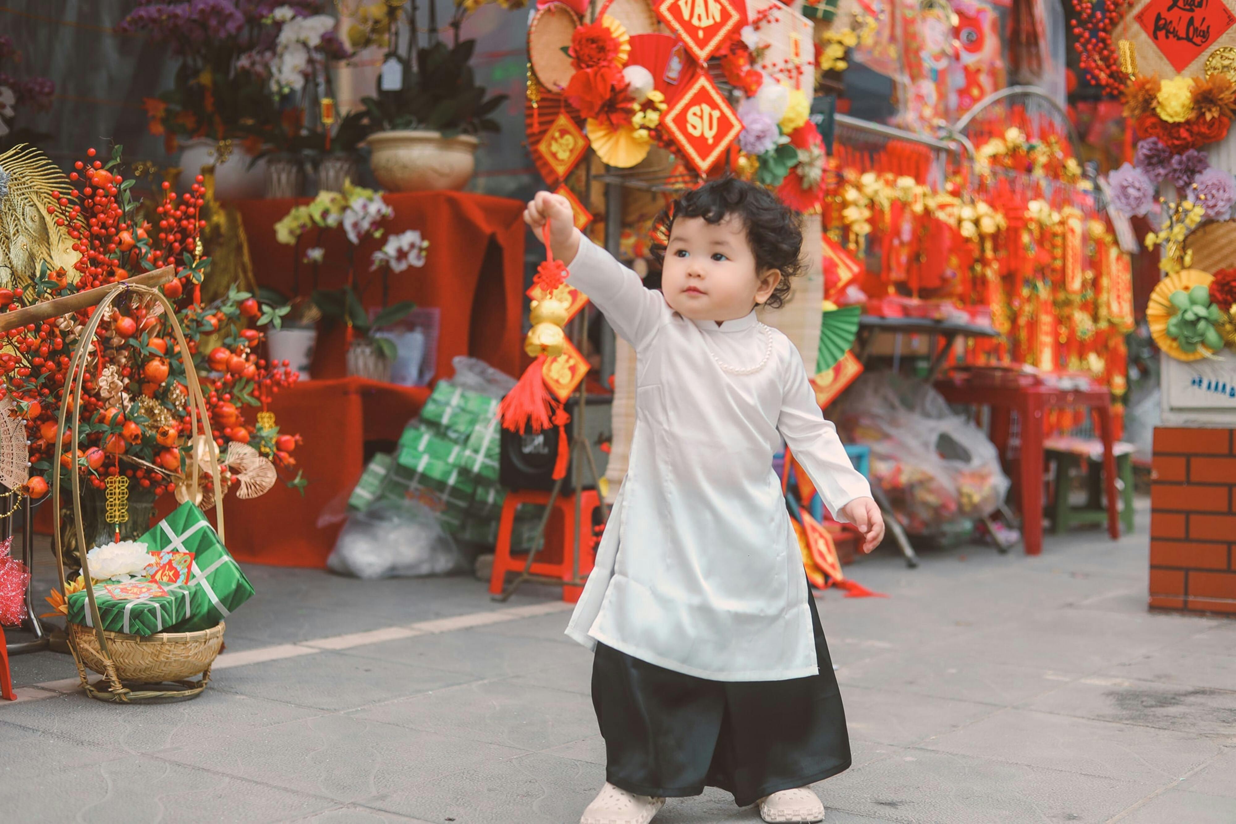 standing child showing lucky cat by souvenirs store