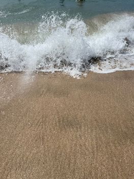 Close-up of ocean waves breaking on a sandy beach, capturing the dynamic motion of water.