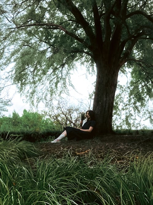 Sitting Woman Smelling Flowers under Tree