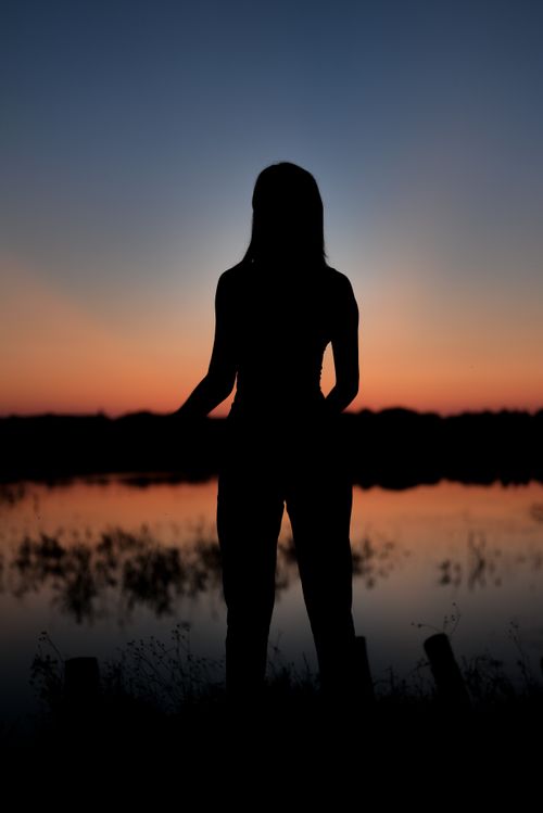 Free A woman's silhouette standing by a tranquil lake at sunset in Garešnica, Croatia. Stock Photo