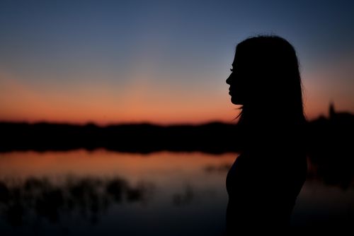 Free Peaceful silhouette of a woman standing by a lake during a colorful sunset in Garešnica, Croatia. Stock Photo
