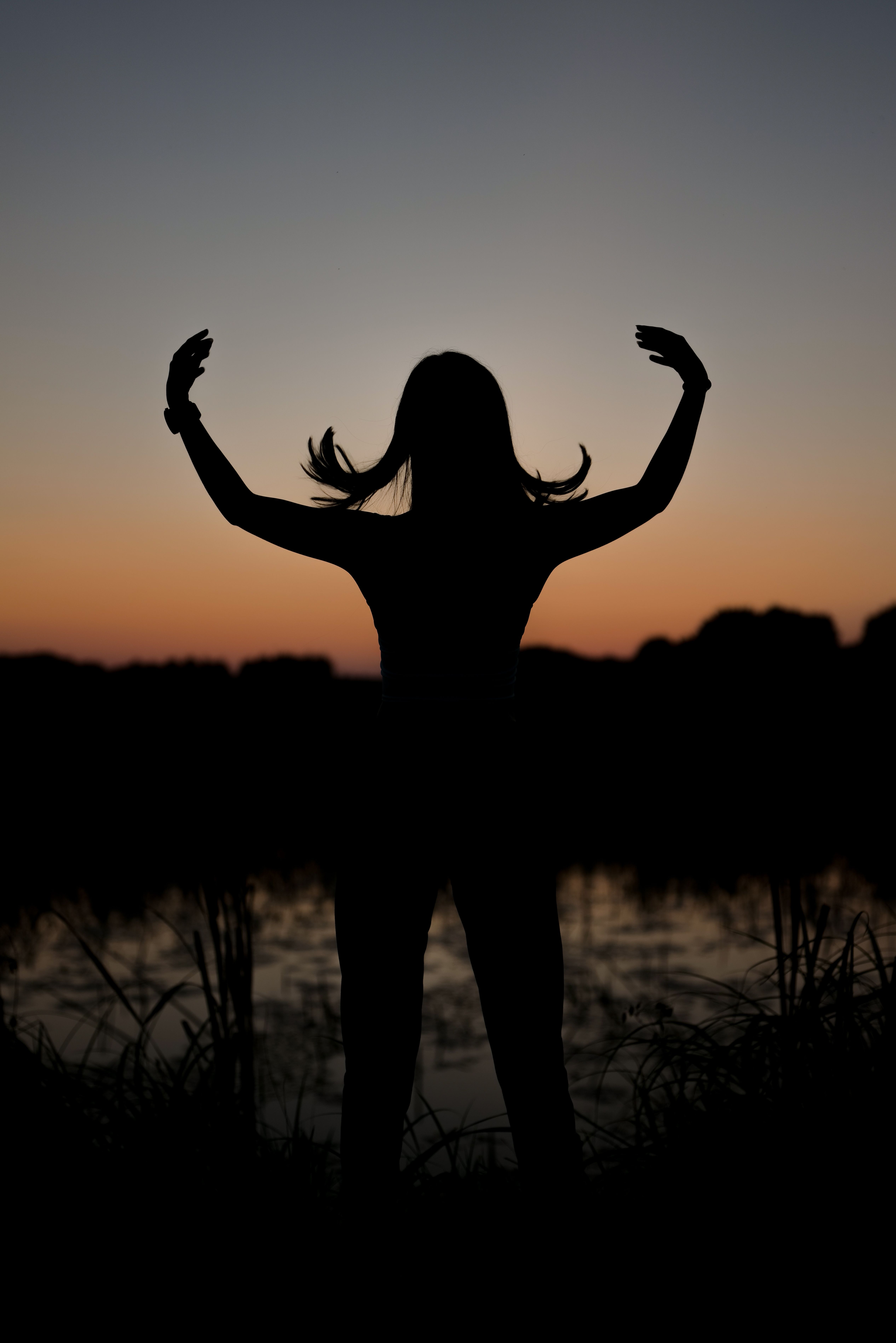 Silhouette of a Woman with Her Arms Outstretched Up Standing by the ...