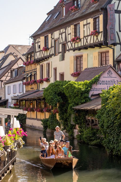 Free Family enjoying a scenic boat ride along a picturesque canal in Colmar, France. Stock Photo
