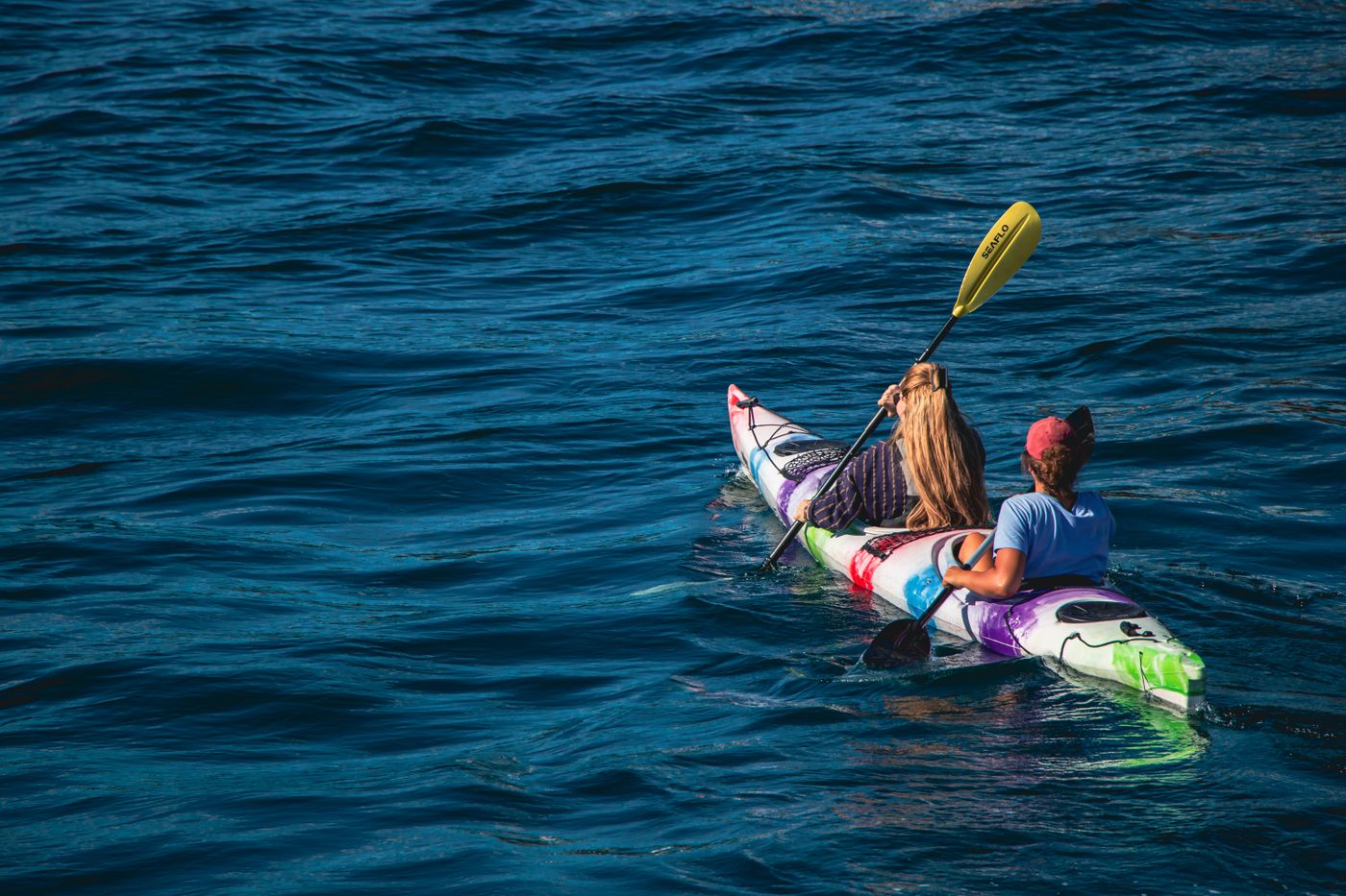 Two people paddling a kayak across calm water