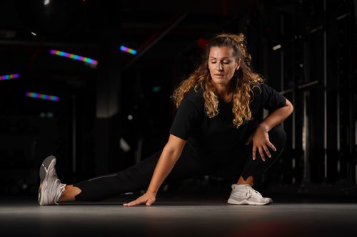 Free Woman stretching in a dimly lit gym in Riga, Latvia, focused on flexibility. Stock Photo