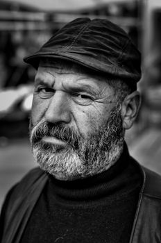 Striking black and white portrait of a bearded man wearing a cap, embodying a rugged look.