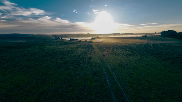 Stunning aerial view of a countryside field at sunrise, enveloped in morning mist.