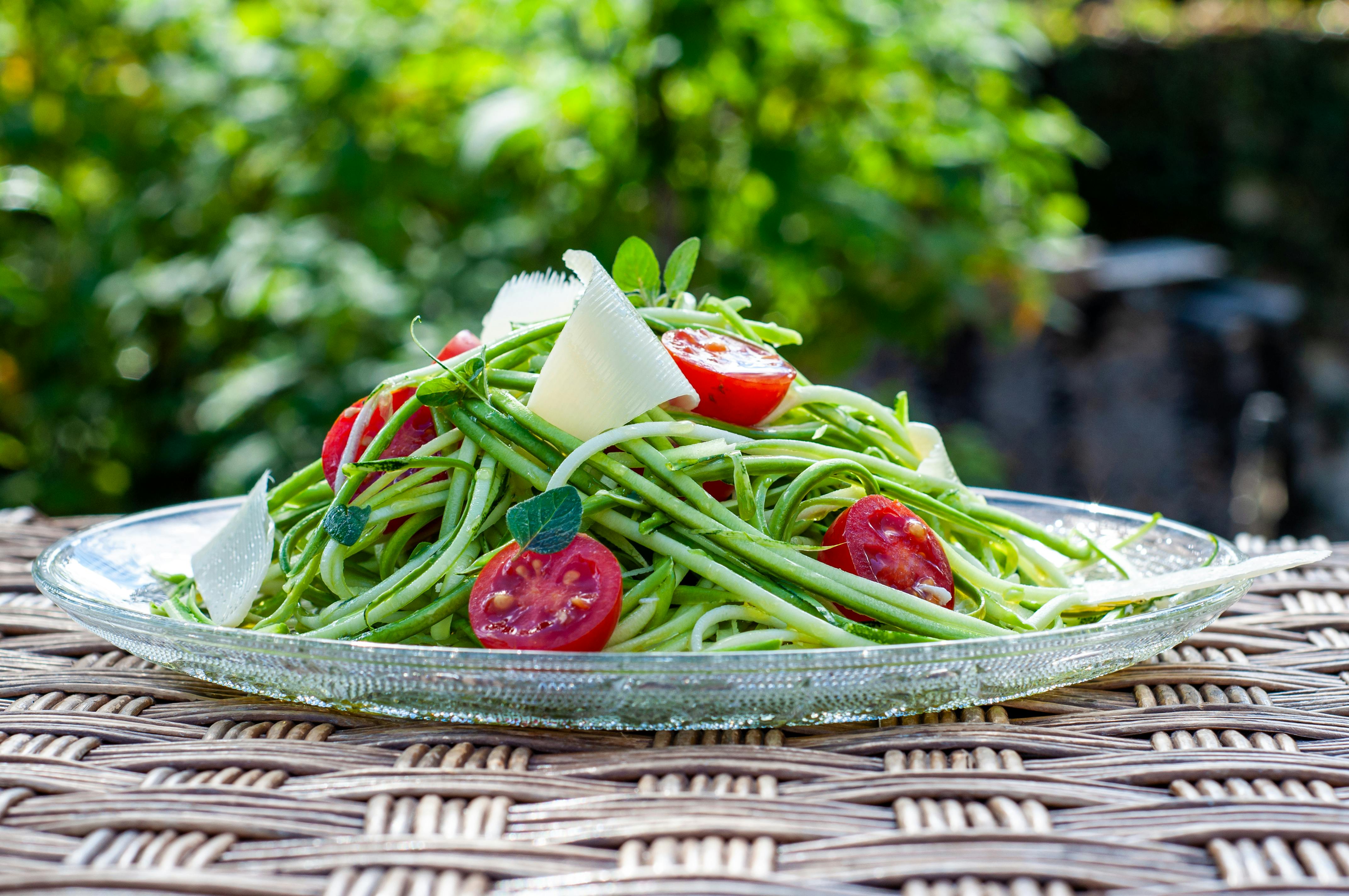 Delicious zucchini spaghetti salad with cherry tomatoes and parmesan on a sunny day.
