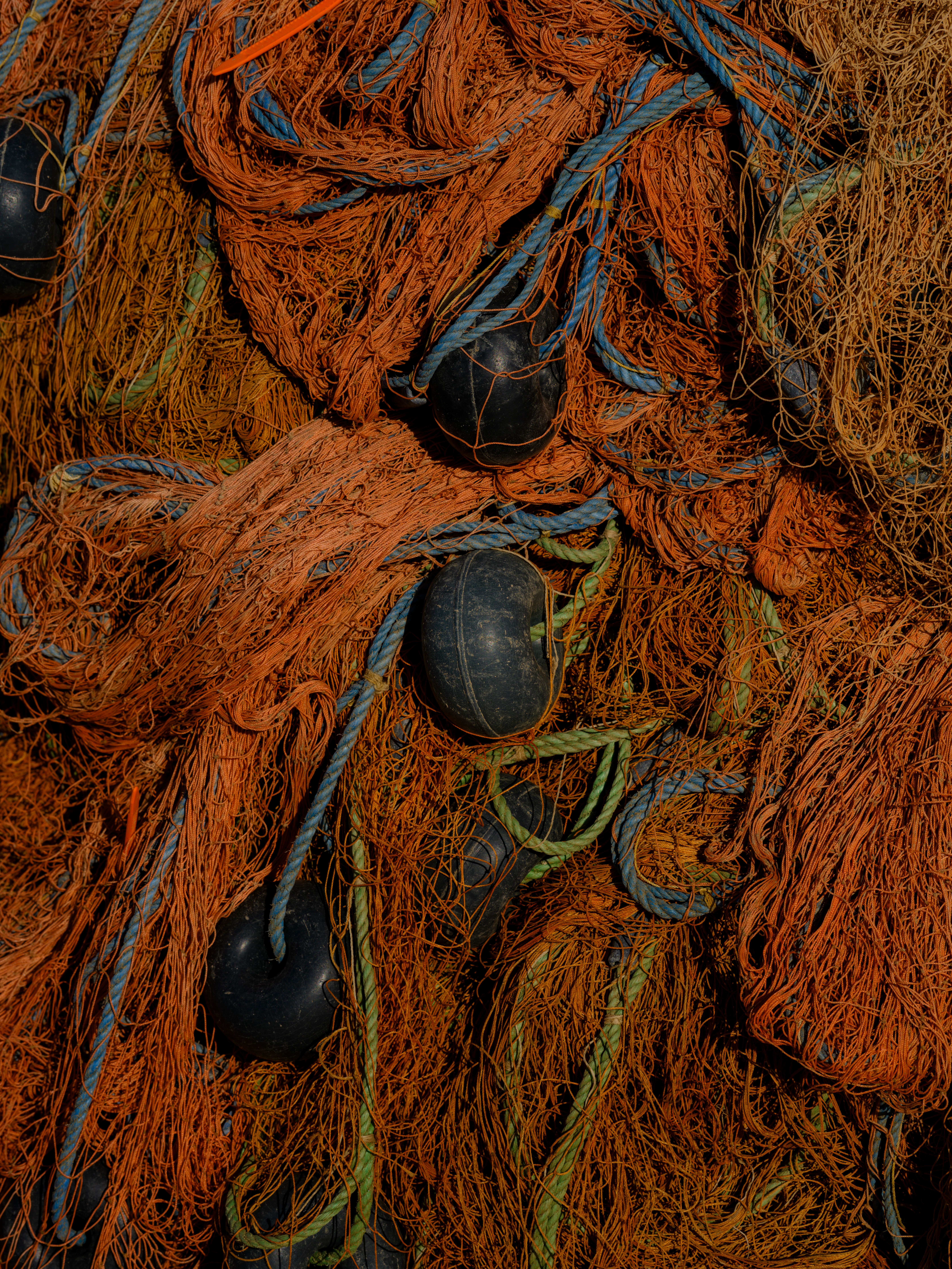 Detailed view of tangled orange fishing nets with floats and ropes.