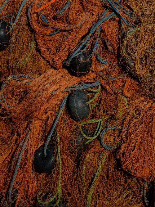 Free Detailed view of tangled orange fishing nets with floats and ropes. Stock Photo