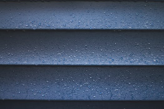 Detailed texture of rain droplets on a blue wall, showcasing a wet and textured surface.