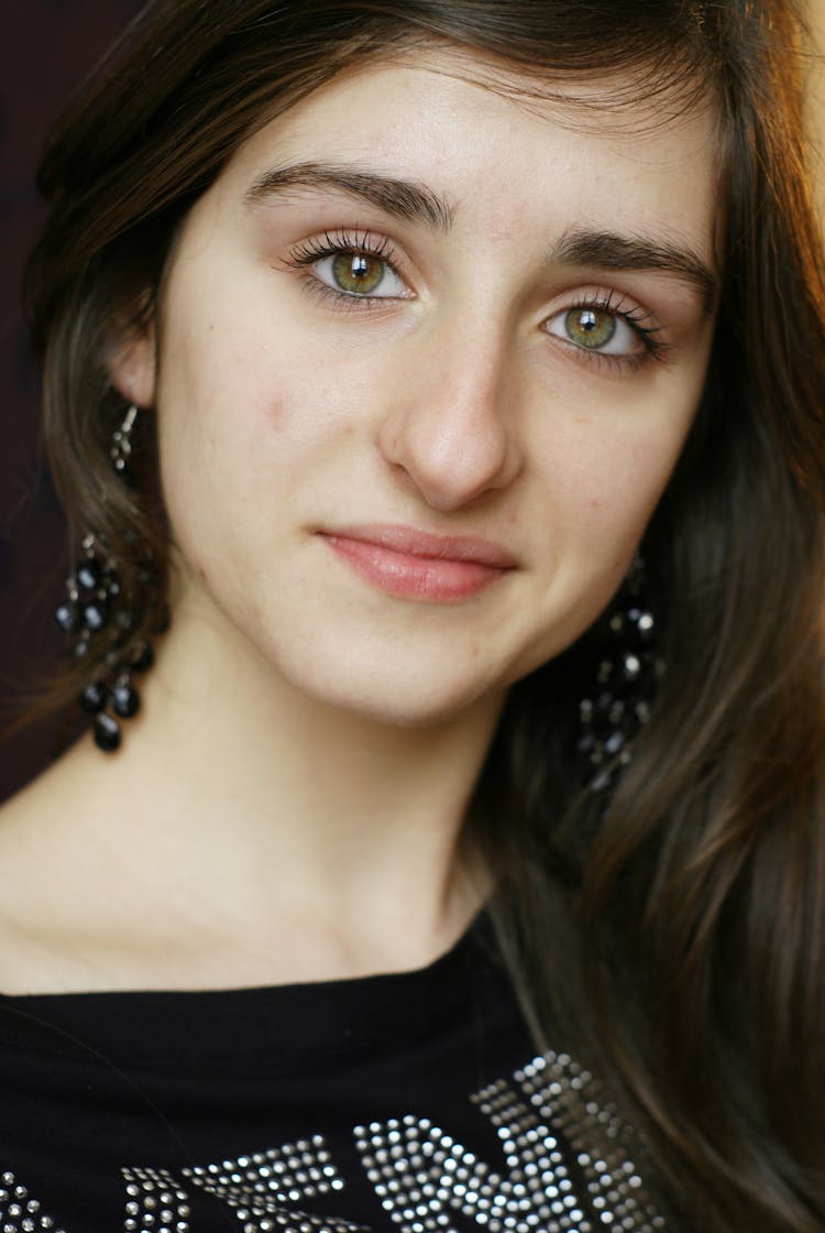 Portrait Of Smiling Brunette Woman With Black Grape Earrings