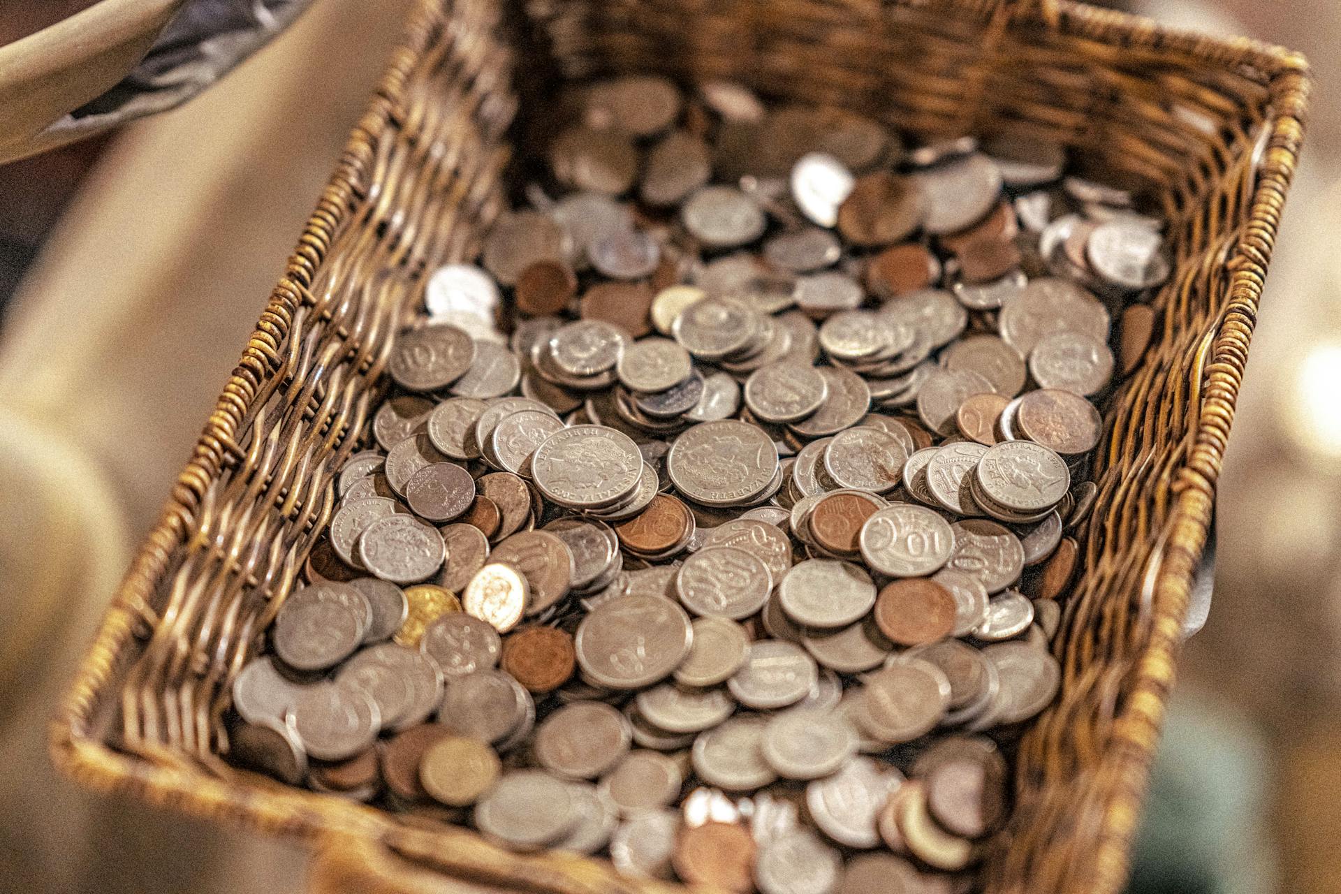 A wicker basket filled with various coins, symbolizing wealth and economic activity.