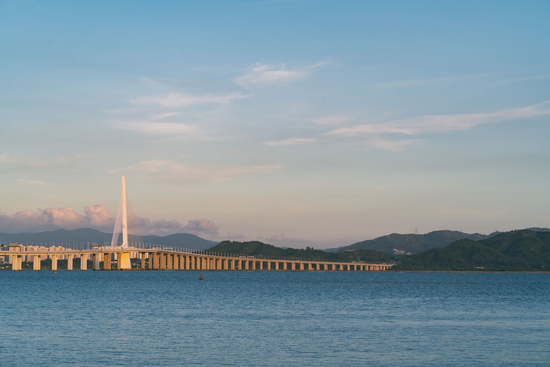 Tranquil scene of Shenzhen Bay Bridge against a serene sunset backdrop over calm waters.
