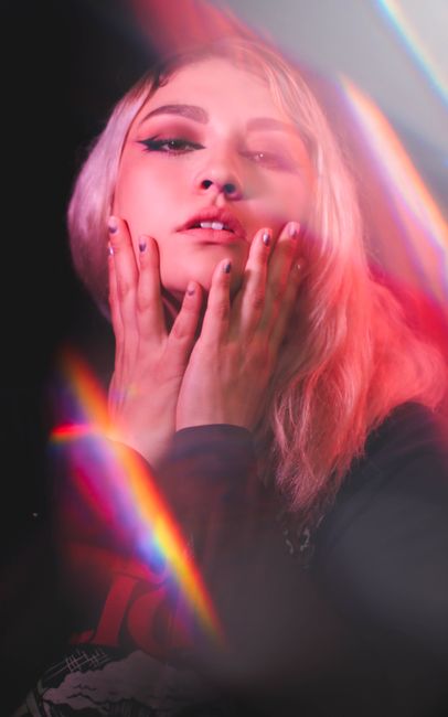 Artistic studio portrait of a woman with colorful lighting and pink hues.
