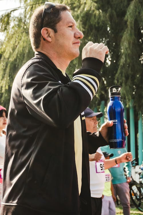 View a Man Drinking from a Flask while Running a Marathon 