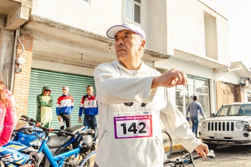 Elderly Man Running a Marathon on a Street in City