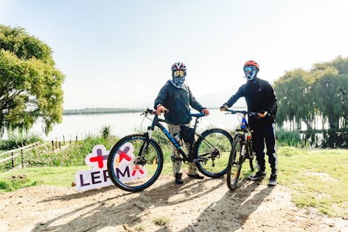 Men Wearing Helmets and Goggles Standing in a Park with Their Bicycles 