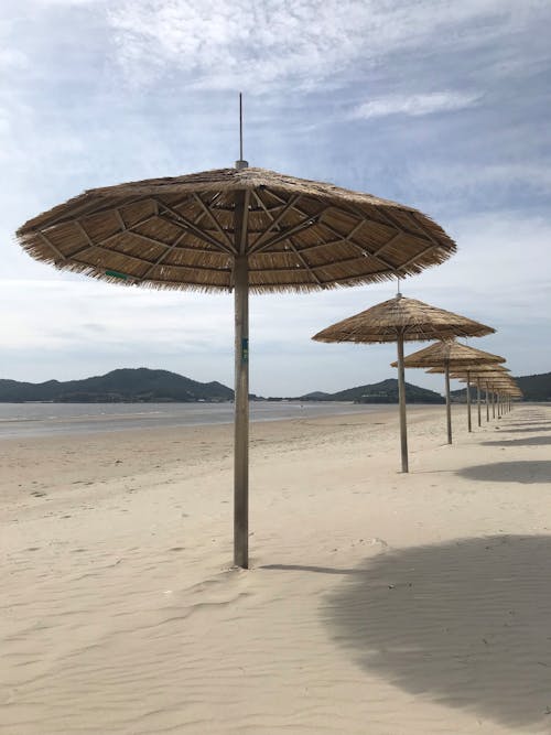 Straw Umbrellas on Sand Beach