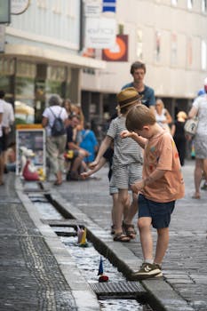 Kids enjoy playing with toy boats in the historic streets of Freiburg, Germany.