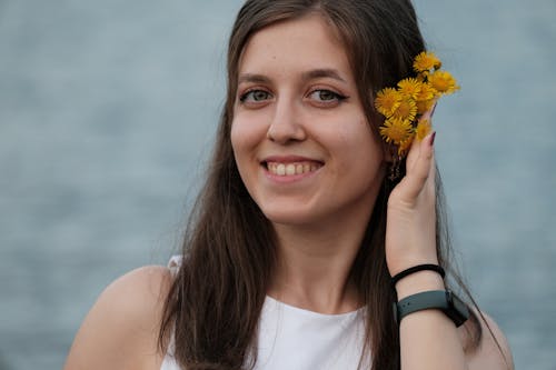 Young Woman with Flowers behind Her Ear Smiling 
