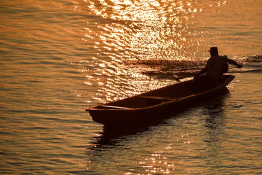 A lone boatman navigates tranquil waters at sunset near Iquitos, Peru, creating a serene silhouette.