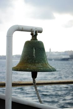 A close-up view of a weathered ship bell on a misty shoreline, evoking a nautical charm.
