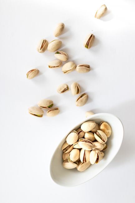 Hạt Dẻ Cười: Lợi Ích Cho Hệ Miễn Dịch & Cách Chọn Loại Không Tẩy Trắng 2026 3 Pistachio nuts in a white bowl on a white background, top view.
