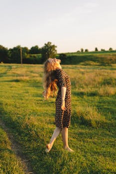 A carefree woman in a floral dress enjoys a summer evening in a rural field.