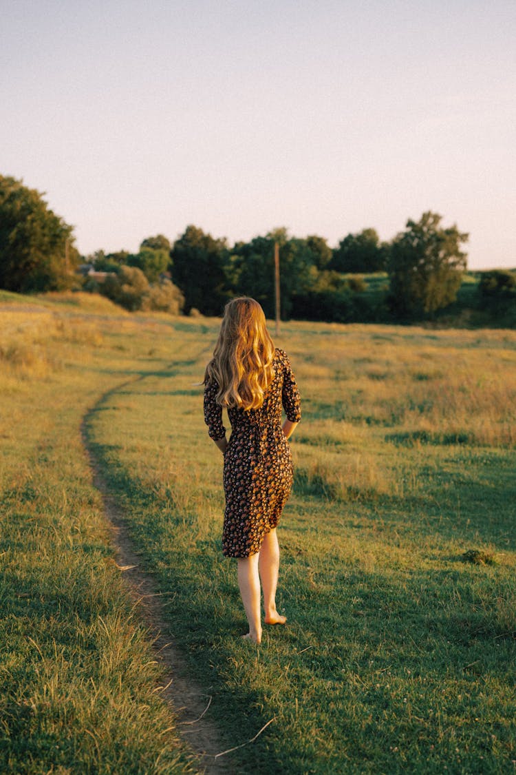 Woman Walking On A Field In Summer
