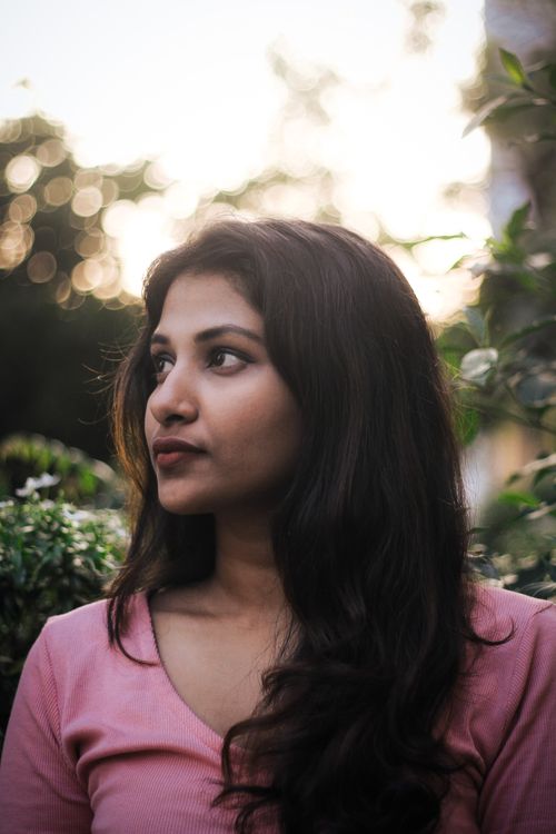 Free Portrait of a woman in natural light, serene and thoughtful mood outdoors. Stock Photo