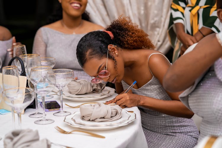 Young Woman In Eyeglasses Writing At A Restaurant Table