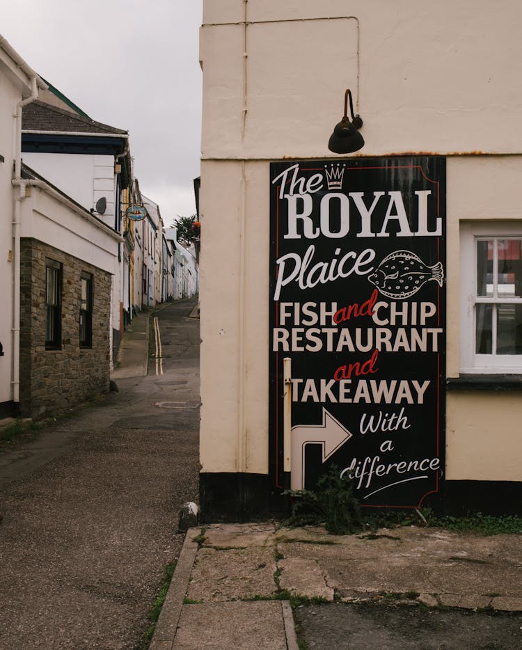 A Sign For A Fish And Chips Restaurant On A Building In A Town 